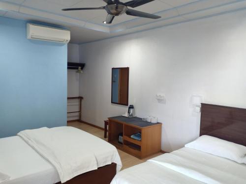 a hotel room with two beds and a ceiling fan at Suhaila Palace in Perhentian Islands