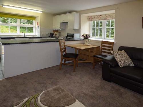 uma cozinha e sala de estar com uma mesa e um sofá em Cockley Beck Cottage em Coniston