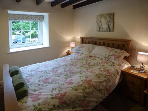um quarto com uma cama grande e uma janela em Cockley Beck Cottage em Coniston