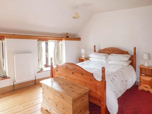 een slaapkamer met een houten bed met witte lakens en kussens bij Tuc - Tin in Clun
