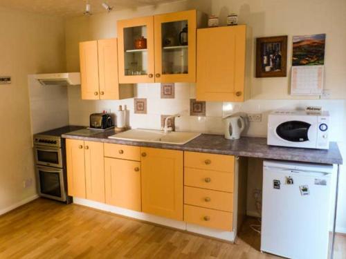 a kitchen with yellow cabinets and a white microwave at 2A Bridge Apartments in Masham