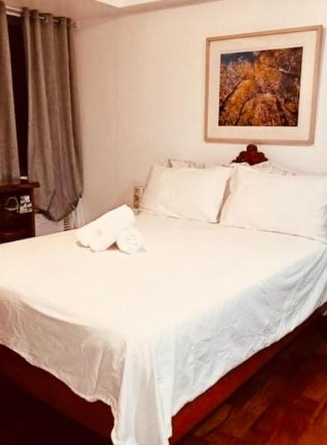 een slaapkamer met een wit bed met een handdoek erop bij 14d mosaic staycation in Manilla