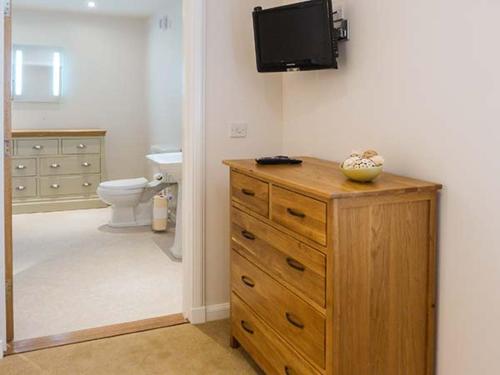 a bathroom with a wooden dresser with a television on a wall at The Auld Kirk in Forsinain