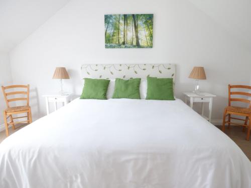 um quarto com uma grande cama branca com almofadas verdes em The Stables, Crayke Lodge em Crayke