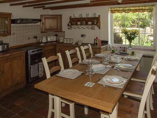 a kitchen with a wooden table with chairs and a dining room at George Cottage in Clun