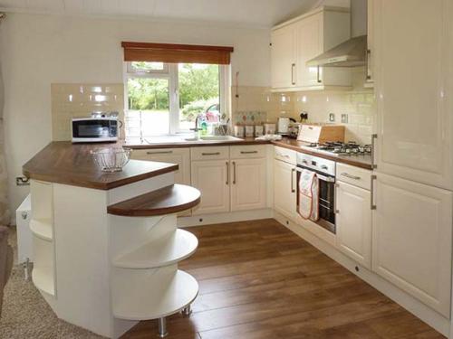 a kitchen with white cabinets and a counter top at Chaffinch Lodge in Highampton