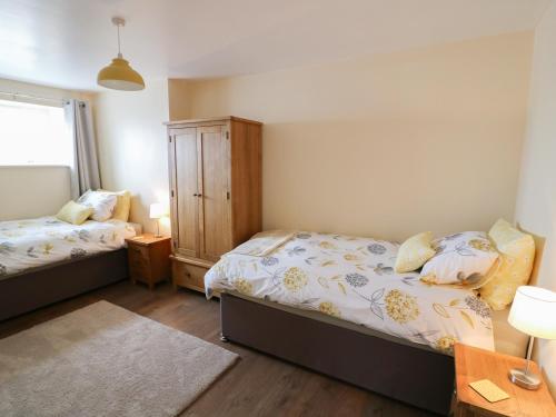 a bedroom with two beds and a wooden cabinet at Ysgubor - The Barn in Newchapel