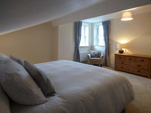 a bedroom with a white bed with a dresser and a window at Hillside View in Hawes