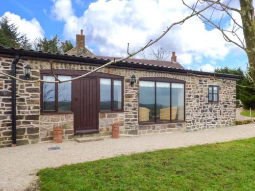 a stone house with windows and a wooden door at Upper Greenhills Farm in Foxt