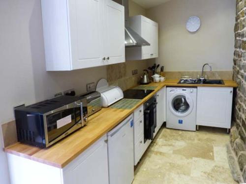 a kitchen with a microwave and a washer and dryer at Upper Greenhills Farm in Foxt