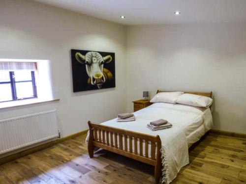 a bedroom with a bed with a picture of a cow on the wall at Upper Greenhills Farm in Foxt