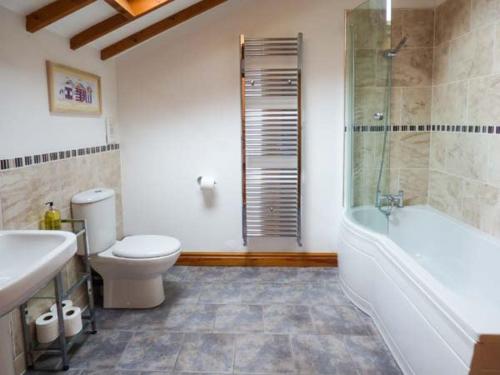 La salle de bains est pourvue de toilettes, d'une baignoire et d'un lavabo. dans l'établissement The Barn Ivy Cottage, à Dunnington