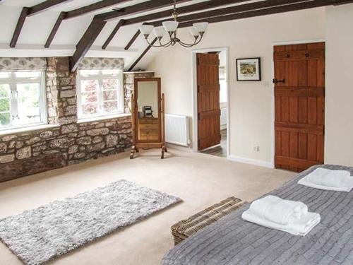 a bedroom with two beds and a stone wall at Ganarew Cottage in Whitchurch