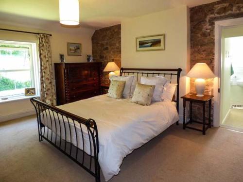 um quarto com uma cama grande com lençóis brancos e almofadas em New House em Bewcastle