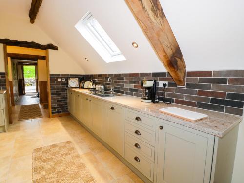 a kitchen with white cabinets and a brick wall at Tyn Y Celyn Isaf in Clocaenog