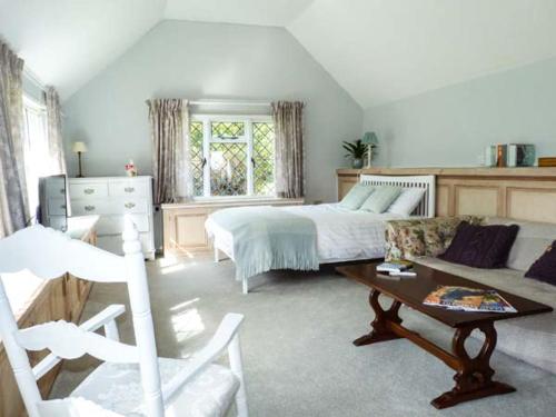 a bedroom with a bed and a couch and a table at Standard Hill Cottage in Ninfield