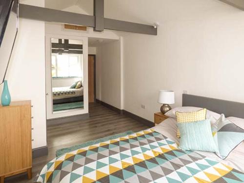 una camera da letto con un letto con una coperta colorata sopra di White Cottage Annexe a Tenby