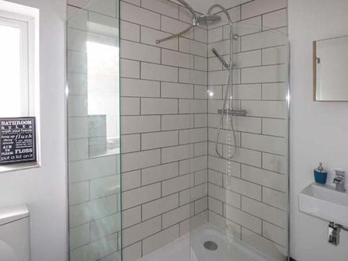 un bagno con doccia con porta in vetro di White Cottage Annexe a Tenby