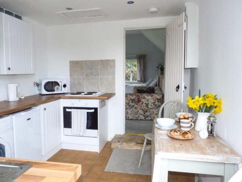 a kitchen with white cabinets and a table with food on it at Standard Hill Cottage in Ninfield