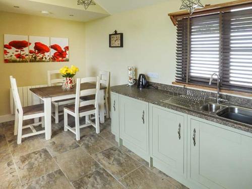 a kitchen with a sink and a table with chairs at Black Mountain View in Llanafan-fawr