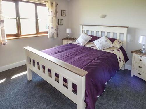 um quarto com uma cama grande com lençóis e almofadas roxos em Black Mountain View em Llanafan-fawr