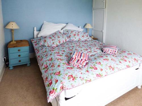 a bedroom with a white bed with a blue wall at Sandy Knowes in Amble