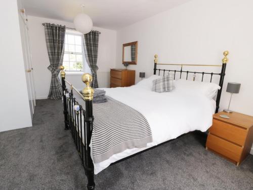 a bedroom with a black and white bed and a window at Dermot Cottage in Gatehouse of Fleet