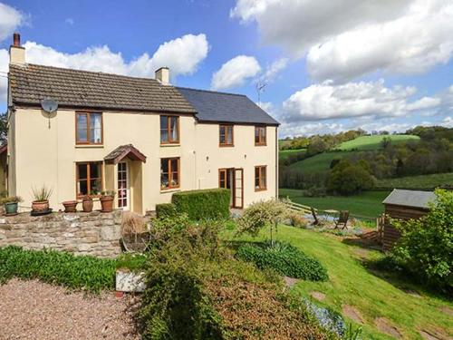 a large white house in a field with a yard at Glebe Farm Cottage in Pontnewydd