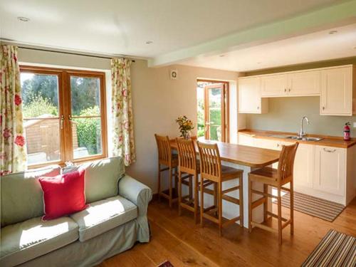 a living room with a couch and a table and a kitchen at Glebe Farm Cottage in Pontnewydd