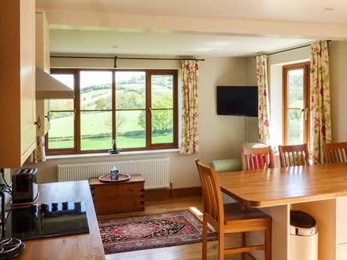 a living room with a dining table and a large window at Glebe Farm Cottage in Pontnewydd