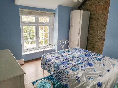 a bedroom with a bed with a blue wall at St Margaret's Cottage in Chardstock