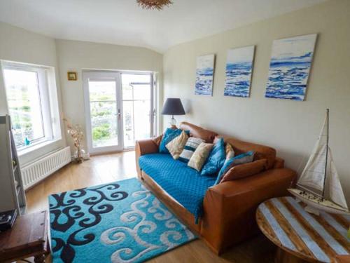 a living room with a couch and a blue rug at Ty'r Enfys Bach - Upper in Trearddur