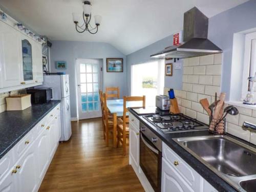 a kitchen with a sink and a stove top oven at Ty'r Enfys Bach - Upper in Trearddur