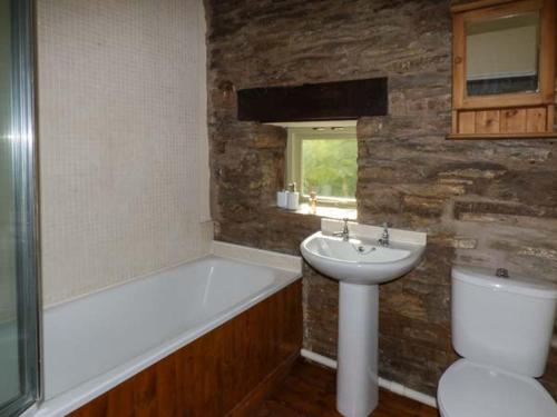 a bathroom with a tub and a sink and a toilet at Ploony Cottage in Bleddfa