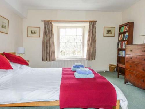 a bedroom with a bed with a red blanket on it at Townhead Farmhouse in Patterdale