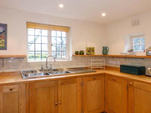 a kitchen with wooden cabinets and a sink and a window at Townhead Farmhouse in Patterdale