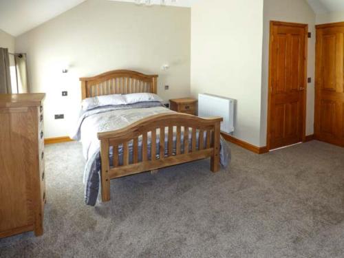 a bedroom with a wooden bed and a tv at Bank Top in Earl Sterndale