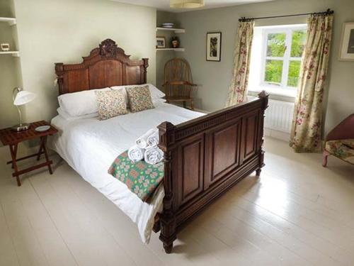 a bedroom with a large wooden bed and a window at Gatehouse in Painscastle