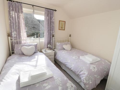 a bedroom with two beds and a window at The Nook at Timbers in Great Longstone