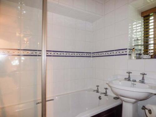 uma casa de banho branca com um lavatório, uma banheira e um WC. em High House em High Newton