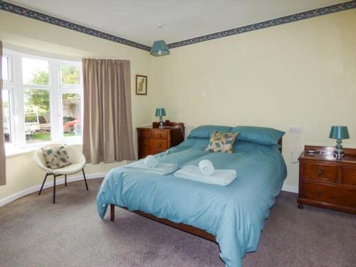 a bedroom with a blue bed and a chair at Glenhaven in Rendham