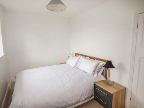- une chambre avec un lit blanc et une table de chevet avec une lampe dans l'établissement Groes Newydd Bach, à Llandecwyn
