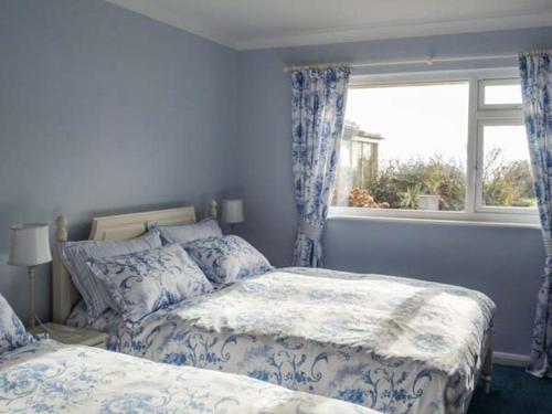 a blue bedroom with two beds and a window at Herbrand House in Bexhill