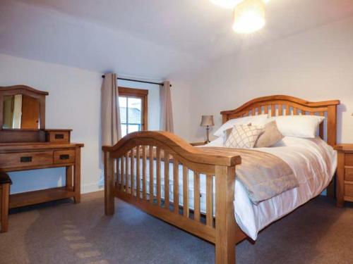 a bedroom with a wooden bed with a dresser and a mirror at Cinderbarrow Cottage in Levens