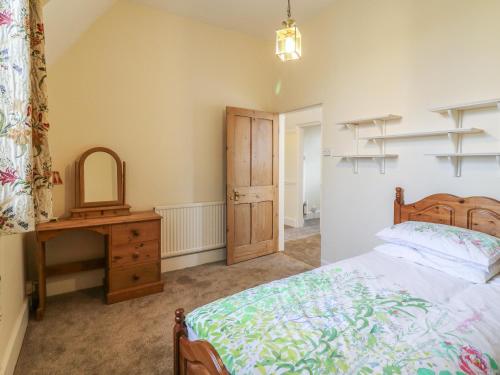 a bedroom with a bed and a dresser and a mirror at 3 Old Police Station in Dunster