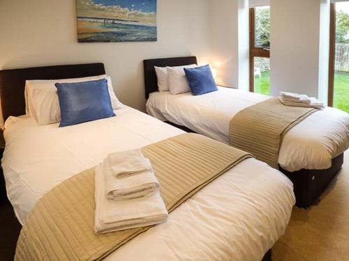two beds in a room with towels on them at Everdene in Broadwey