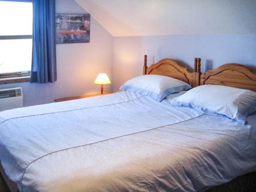 a bedroom with a large white bed and a window at Stemster School House Apartment in Castletown