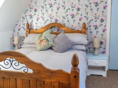 a bedroom with a wooden bed with flowers on the wall at Deskford Cottage in Balblair