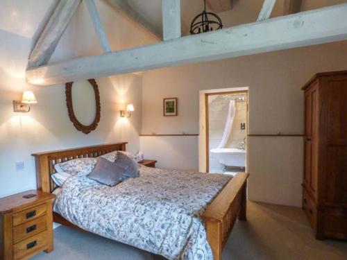 a bedroom with a large bed and a mirror at Fire Brigade Barn in Tissington
