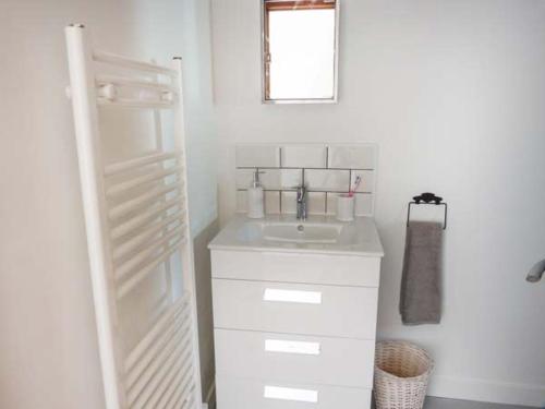 a white bathroom with a sink and a mirror at Deskford Cottage in Balblair